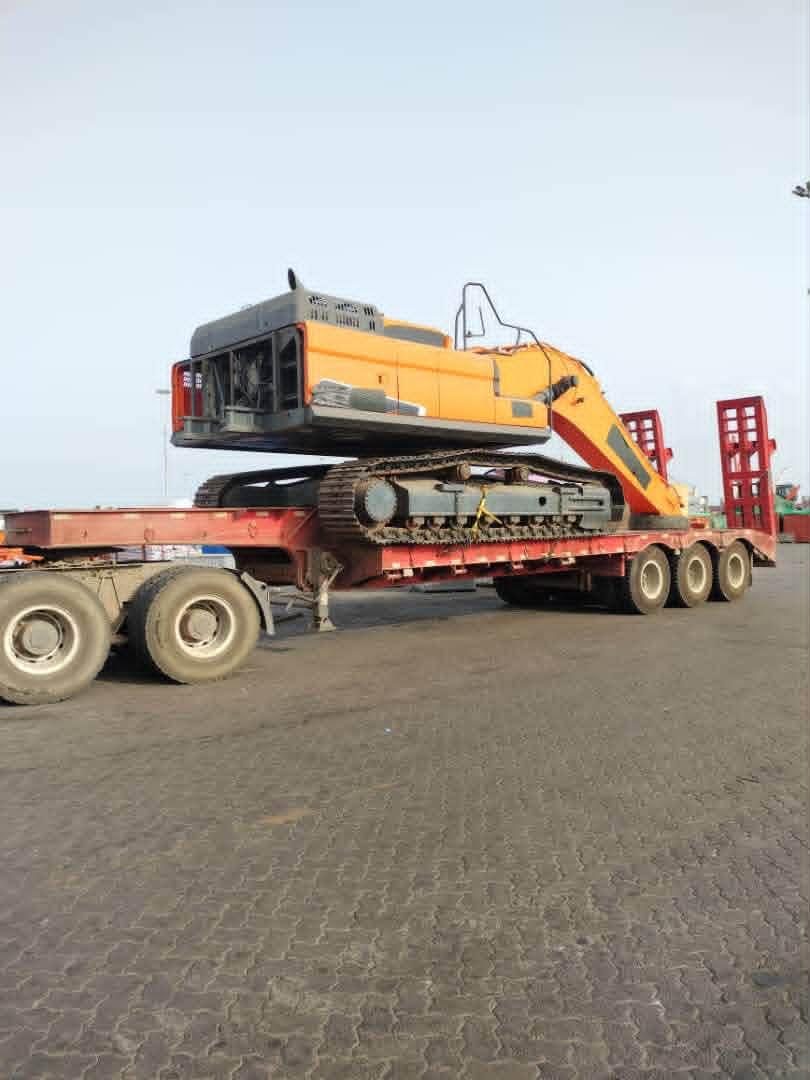 Orange excavator on a low-bed trailer at a port